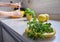 Yellow plate with oregano leaves and background with woman`s hands preparing healthy food