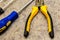 Yellow pliers focus on pens screwdriver screw fixing furniture repair techniques close-up