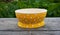 Yellow polka dots fashionable bright plastic dishes for the kitchen on a wooden table on a background of green grass