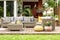 Yellow pouf and flowers next to rattan garden furniture on wooden terrace of house. Real photo