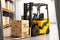 Yellow powerful forklift delivering boxes with goods to warehouse