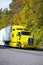 Yellow powerful semi truck with reefer trailer on autumn road