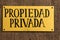 Yellow private property sign on a wooden door in Caceres.