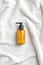 Yellow pump cosmetic bottle on white towel top in bathroom, top view.