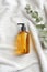 Yellow pump shampoo bottle and eucalyptus leaf on white towel.