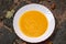 yellow pumpkin cream soup in white plate Halloween, autumn comfort food