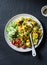 Yellow pumpkin lentils, roasted turmeric cauliflower and vegetables in one bowl - vegetarian food on a dark background,
