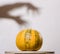 Yellow pumpkin no table with hands shadow on wall