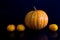 Yellow pumpkin and oranges photo on black background.