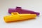 A yellow and purple kazoo on white background