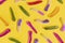 Yellow, purple, red, pink and green sugar coated jelly worms pattern on a yellow background