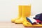 Yellow rain boots and outumn outfit. Autumn fashion. Stylish gumboots and coat on wooden shelf