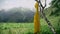 A yellow raincoat hangs on a birch tree in a mountainous area in summer. Beautiful landscapes