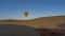 A yellow-red balloon is flying in a clear blue sky over the desert.