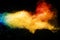 Yellow red blue powder explosion cloud on black background. Freeze motion of color dust  particles splashing