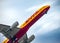 Yellow and Red DHL cargo aircraft jumbo jet taking off towards a blue sky with clouds blurring from motion.