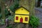 Yellow and red fairy door attached to the base of a tree trunk in an Irish woodland fairy garden.