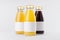 Yellow, red fruit and berries juices collection in glass bottles with cap, white blank labels, group, mock up on white background.