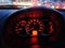 Yellow Red Illuminated Speedometer Console Against Blurred Traffic Background