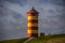 The yellow and red lighthouse of Pilsum with dark clouds in the background