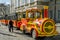 Yellow and red touring car in the form of a train with carriages waiting for tourists landing on a tour is a sunny day at the Mark