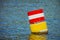 Yellow red and white steel navigational floating buoy in the blu