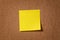 Yellow reminder sticky note on cork board