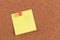 Yellow reminder sticky note on cork board