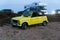 Yellow Renault 4 car oldtimer convertible parked at stony parking by the sea.