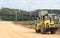 Yellow road roller working on sandy surface