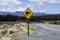 Yellow road sign with kiwi bird crossing by the road. Mountains in the background. Located in the Tongariro National Park, North