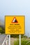 Yellow road sign warning about rock fall danger in Portuguese and English language. The usage of the road is under exclusive and