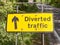 a yellow road traffic construction sign for design graphics saying diverted traffic on the side of a road and with a black upward