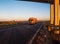 A yellow road train carries cargo against the backdrop of a sunny sunset and blue sky. Concept of work as a truck driver on a