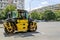 Yellow roller for asphalt tamping moves on the city street to the new constraction site.  Road-building machinery. Improvement of