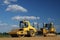 Yellow roller and bulldozer over blue sky