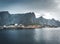 Yellow rorbu houses of Sakrisoy fishing village on a cloudy day with mountains in the background. Lofoten islands