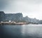 Yellow rorbu houses of Sakrisoy fishing village on a cloudy day with mountains in the background. Lofoten islands