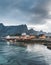 Yellow rorbu houses of Sakrisoy fishing village on a cloudy day with mountains in the background. Lofoten islands