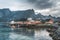 Yellow rorbu houses of Sakrisoy fishing village on a cloudy day with mountains in the background. Lofoten islands