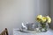 yellow rose in round vase, cup of coffee on grey table on the white background