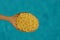 Yellow round cereal in a wooden spoon on a blue background