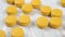 Yellow round medical pill falls into a pile of medicines on a wooden table close-up.