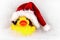 Yellow rubber duck for bathing in a red Santa hat lies in the bathroom among relaxing bubble baths, front view, copy