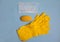 Yellow rubber gloves, medical mask, and Yellow soap lie on a blue background. Purity. Hygiene. Protection. topview