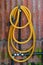 Yellow rubber water hose on rusty galvanized wall