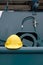 Yellow safety helmet on gunwale of fishing vessel with blurred background of green winch machine