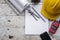 yellow safety helmet and rolled up architectural blueprints on a wooden desk