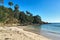 Yellow sand beach view with green trees in jungle woods at the background. Beautiful travel picture. Tropical island landscape.