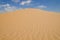 Yellow sand dunes with wavy textures against a blue sky in Swakopmund